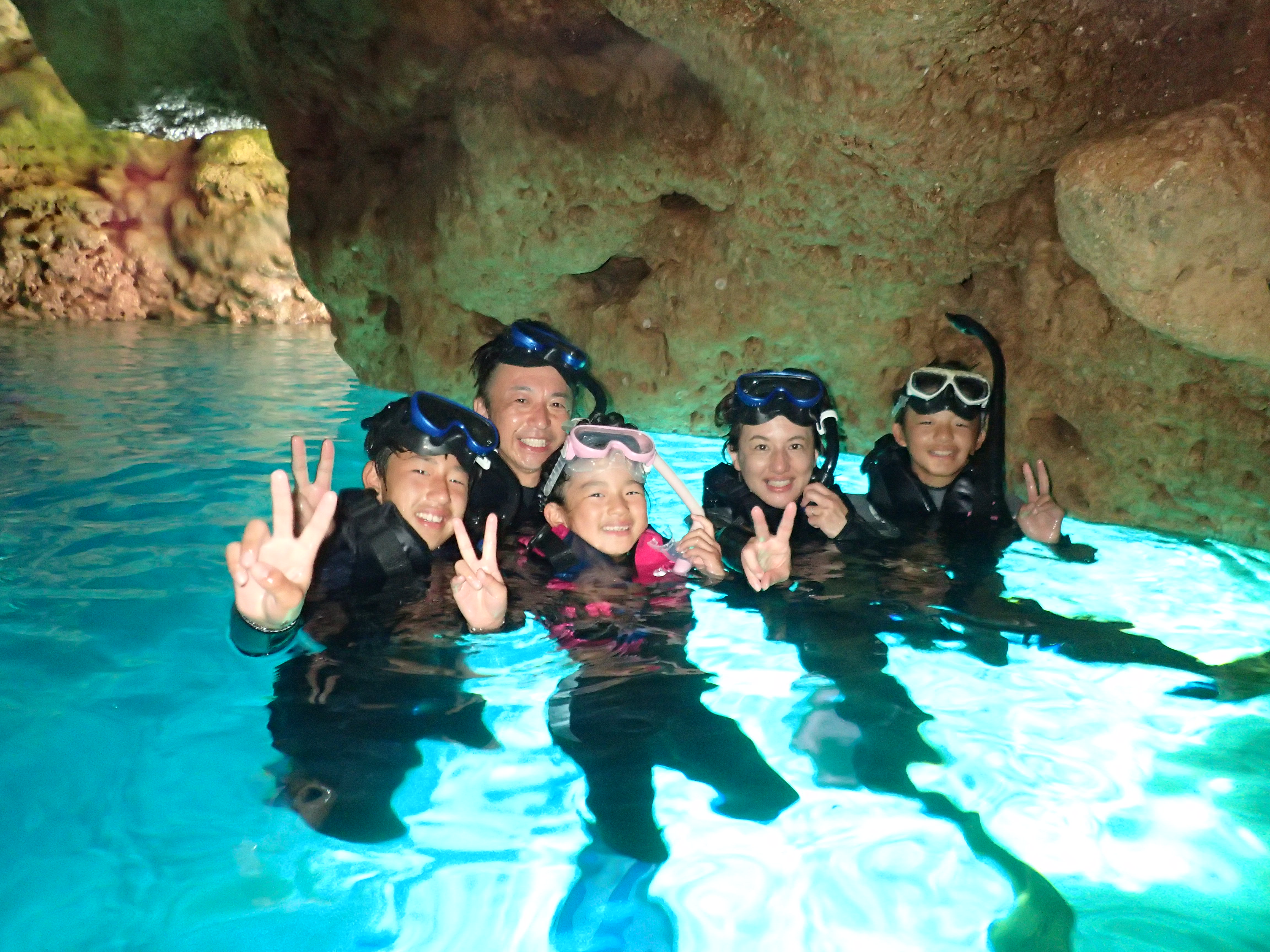 沖縄の青の洞窟でシュノーケリングツアーに参加する親子