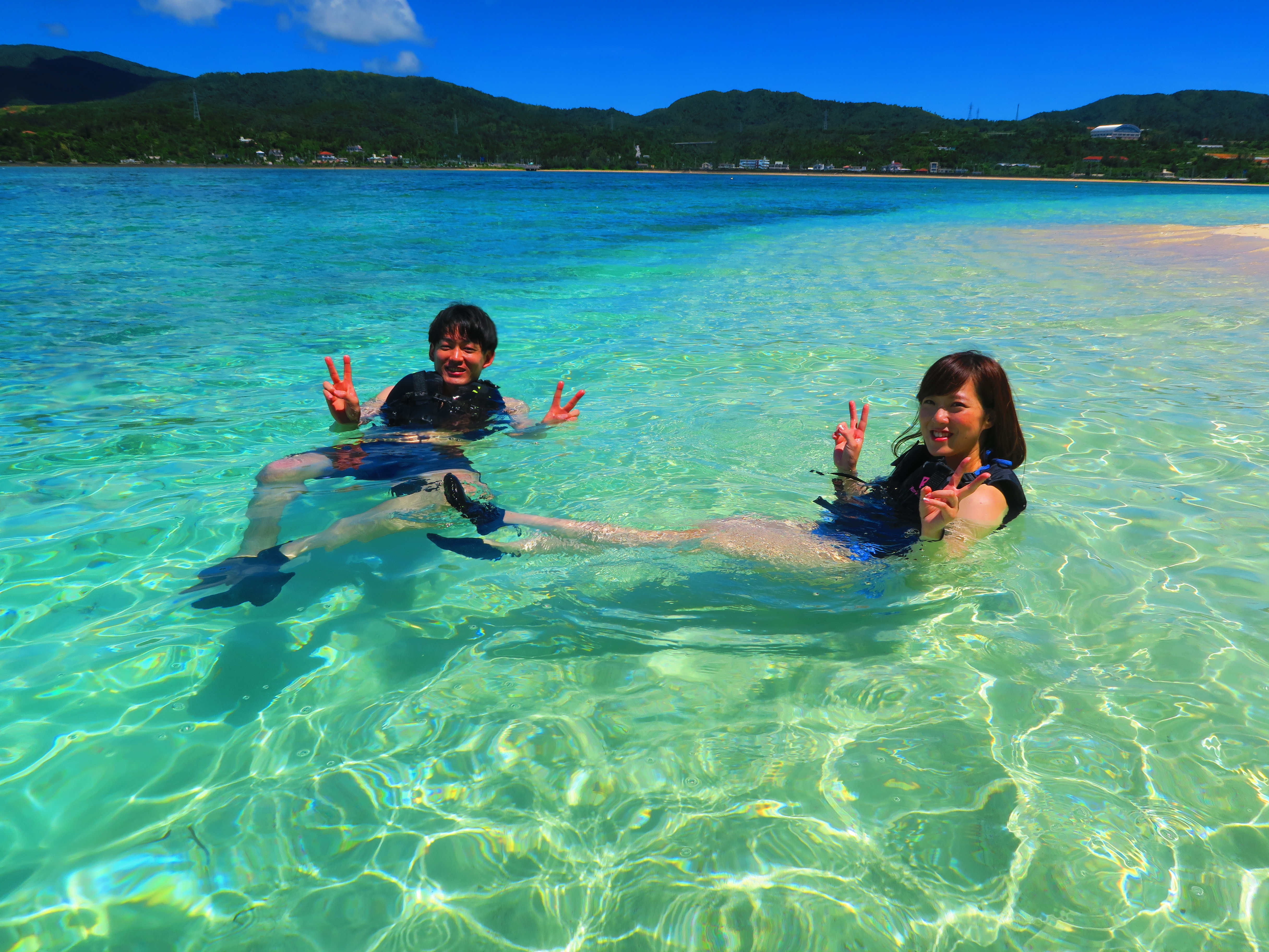 沖縄の恩納村でSUPのあと海に入って楽しむカップル