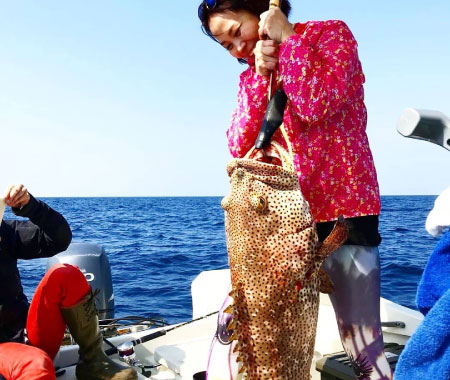 沖縄の海で大きな魚を釣り上げる女性