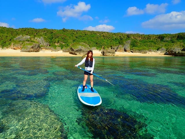 透明度抜群の海でＳＵＰ体験をする女性